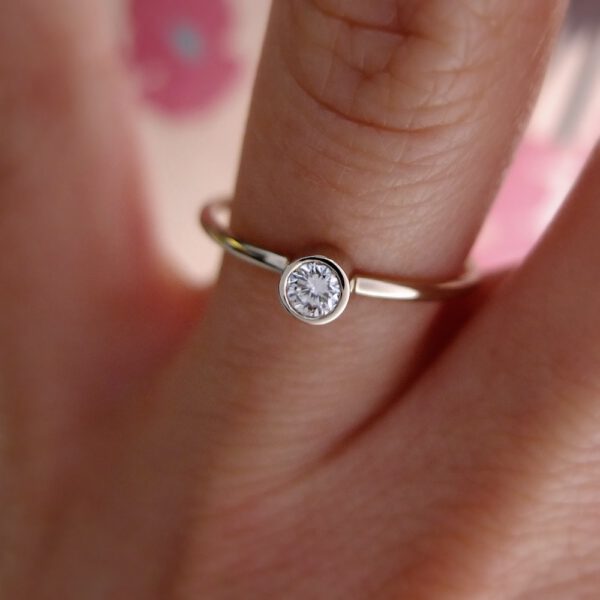 minimalistyczny pierścionek z białego złota z brylantem na palcu