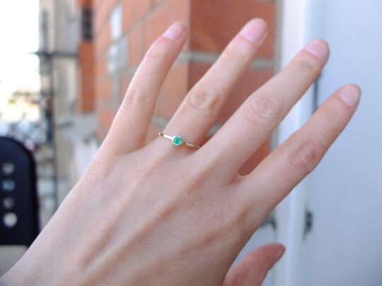 minimalistyczny pierścionek ze szmaragdem na palcu
