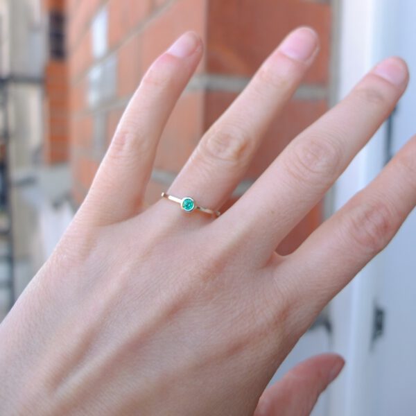 minimalistyczny pierścionek ze szmaragdem na palcu
