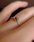 pierścionek fakturowany z ciemną perłą na palcu