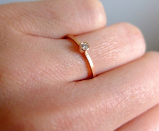 złoty pierścionek z brylantem ze złota na palcu