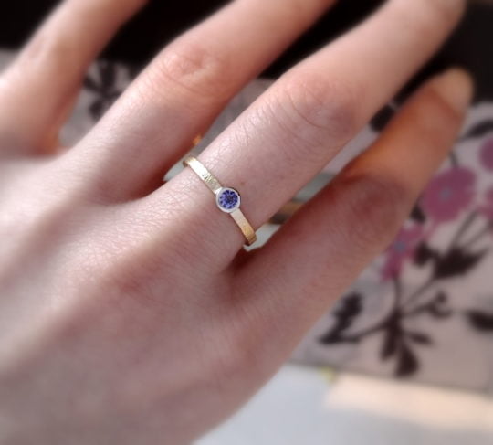 minimalistyczny złoty pierścionek z tanzanitem na palcu