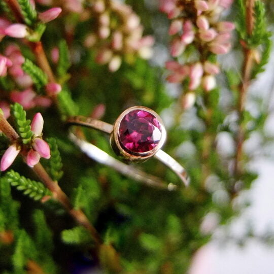 złoty pierścionek bizoe z różowym grantem na tle wrzosu