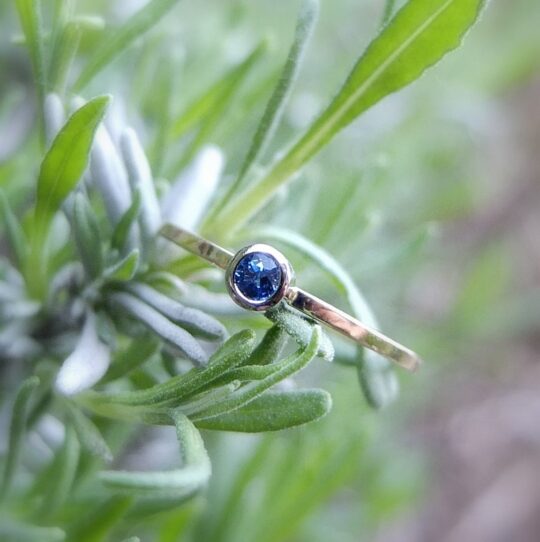 pierścionek zaręczynowy na serdecznym palcu złoty z niebieskim szafirem na gałązce lawendy