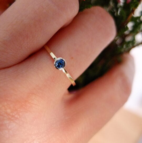 pierścionek zaręczynowy na serdecznym palcu złoty z niebieskim szafirem na palcu